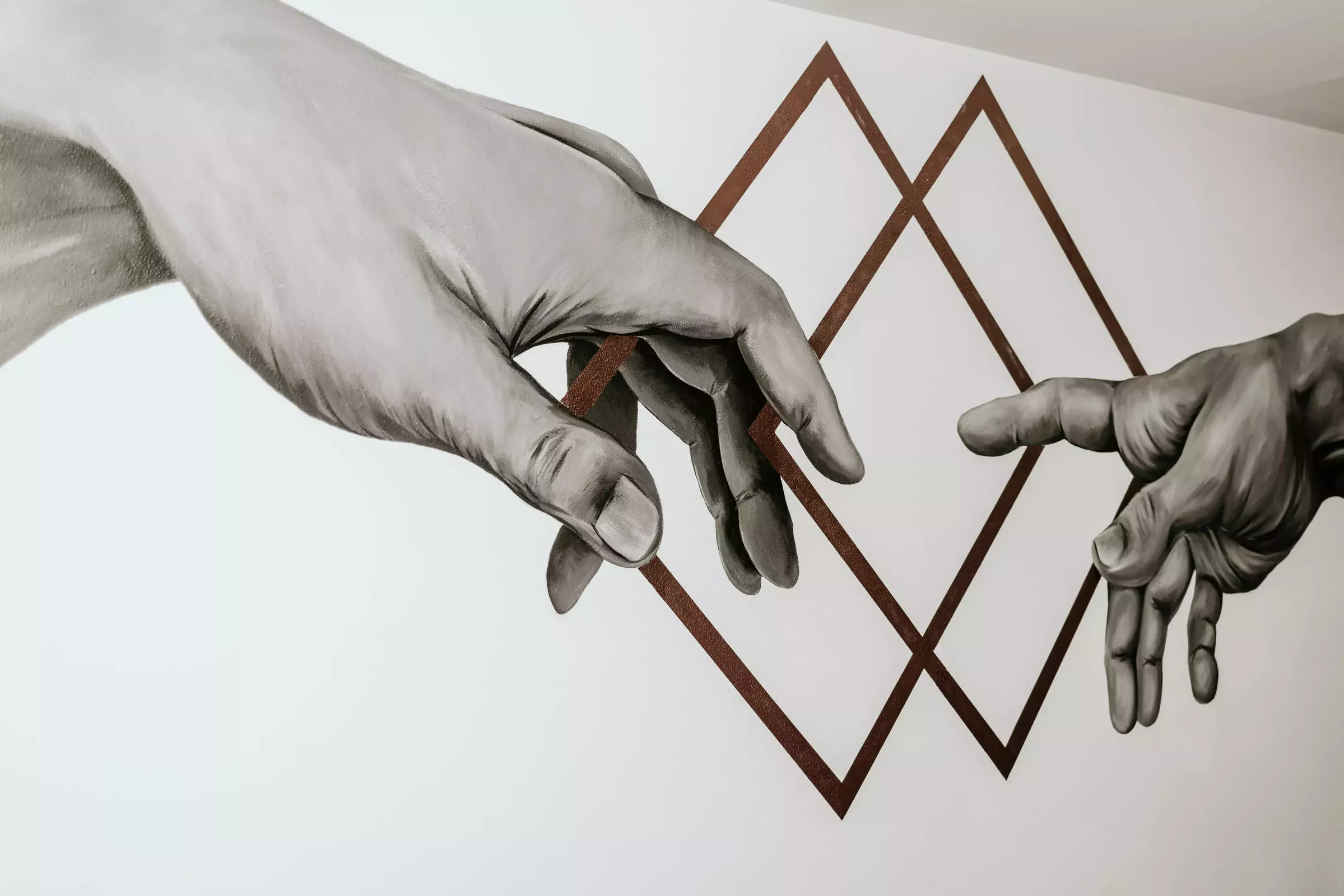 artwork on wall of two hands reaching for one another