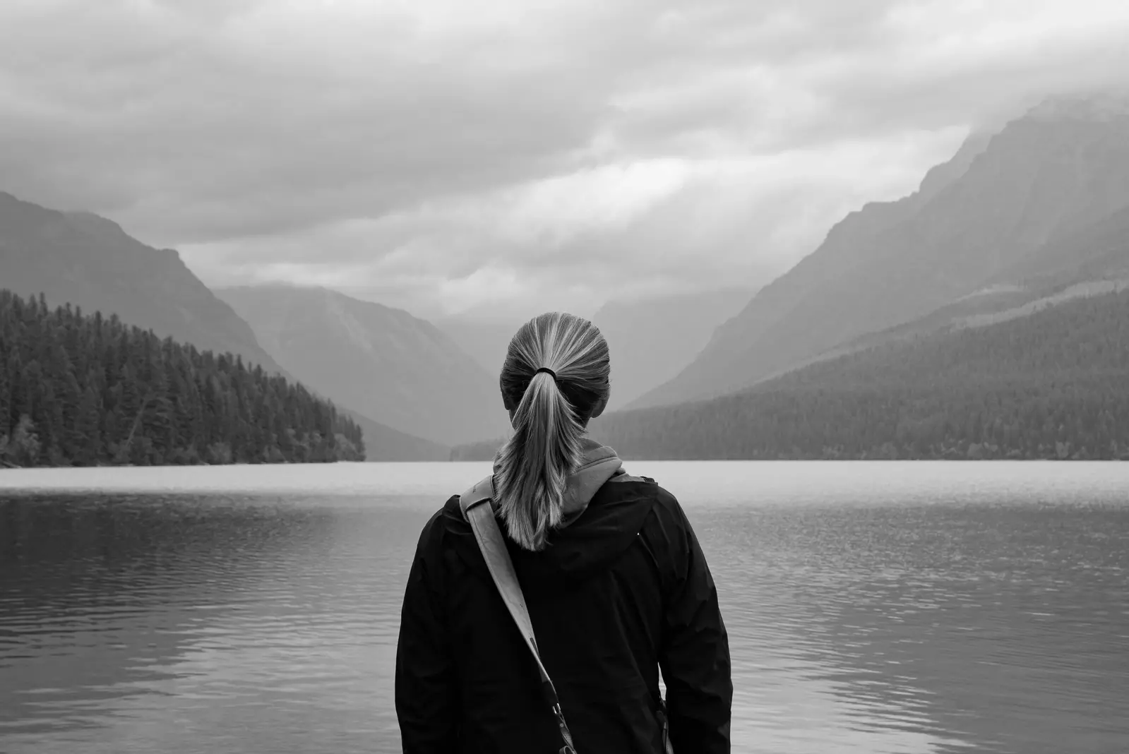 woman looking out over lake surrounded by mountains